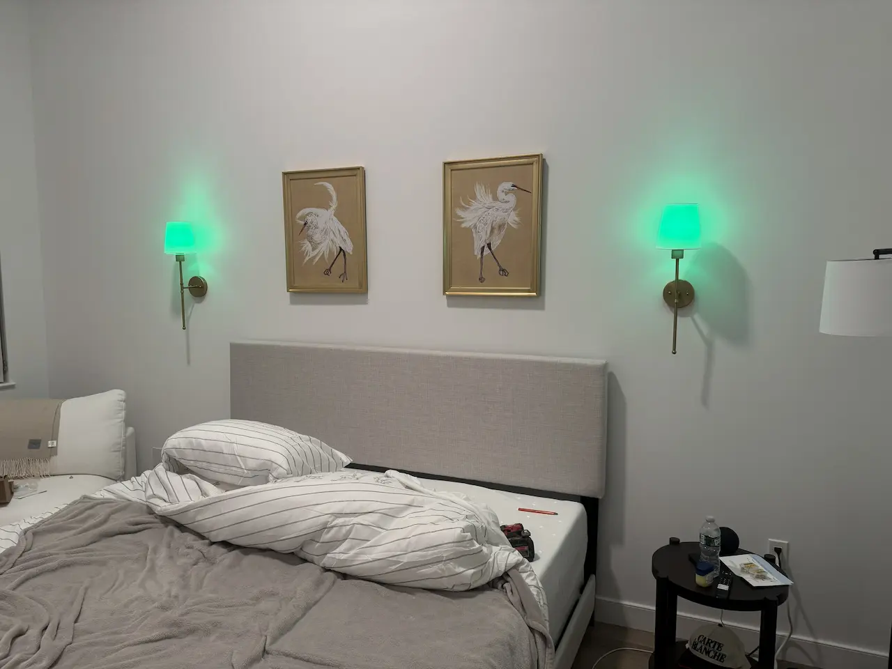 Pair of framed artworks installed symmetrically between wall sconces with even spacing — Brooklyn bedroom